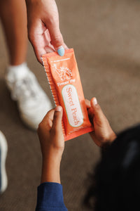 Teacher handing sweet peach EllyPop to a preschool student at Ramalynn Academy